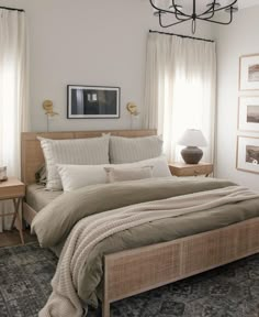 a bedroom with a bed, nightstands and pictures on the wall above it in neutral colors