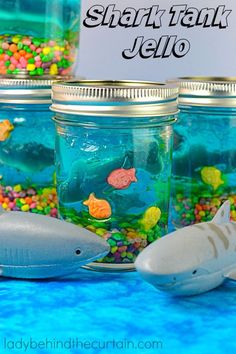 there are many fish in the jar on the table and one shark is next to it