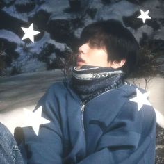 a young man sitting in the snow with stars on his jacket