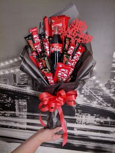 someone is holding up a bouquet of chocolates and candy bar wrapped in red ribbon