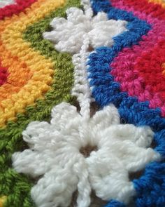 a crocheted blanket with multicolored flowers on it