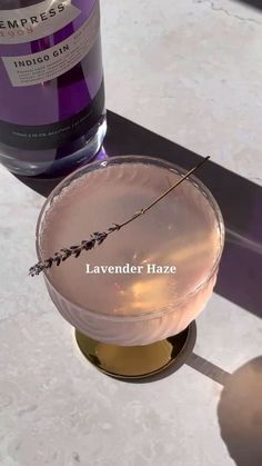 a lavender haze cocktail sitting on a table next to a bottle