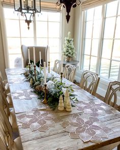 a dining room table decorated for christmas with candles and greenery on the table top