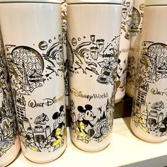 the disney world cups are lined up on the shelf