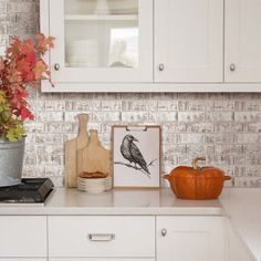 a kitchen with white cabinets and an orange pumpkin on the counter next to a potted plant