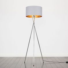 a floor lamp with a white shade on it and a black cord plugged into the base