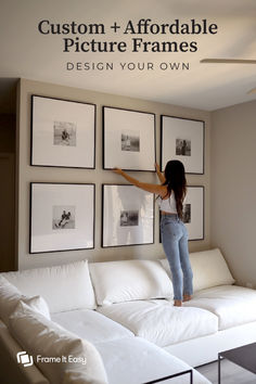 a woman hanging pictures on the wall above a white couch in a living room with text overlay that reads custom and afordable picture frames design your own