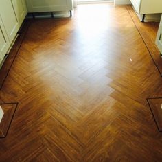 an empty kitchen with wood flooring and white cabinets