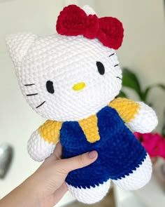 a hand holding a hello kitty crochet doll