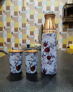 three cups sitting on top of a table next to a bottle