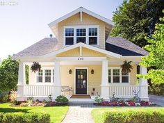 a yellow house with white trim and black shutters on the front door is shown