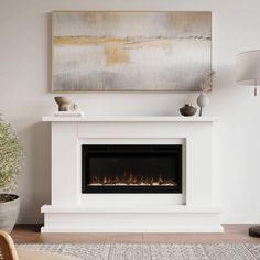 a white fireplace in a living room with a painting on the wall and a potted plant next to it