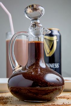 a glass carafe filled with liquid sitting on top of a table next to a can of guinness