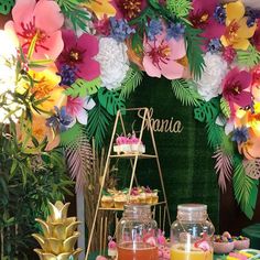 an assortment of desserts and drinks displayed on a table with tropical flowers in the background