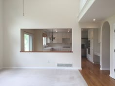 an empty living room with hard wood flooring and large mirror on the wall above it