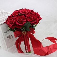 a bouquet of red roses sitting on top of a white box with ribbon around it