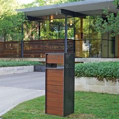 a tall wooden box sitting on top of a grass covered field next to a building