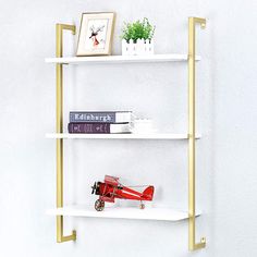 three white shelves with gold handles and books on them, against a white wall in a living room