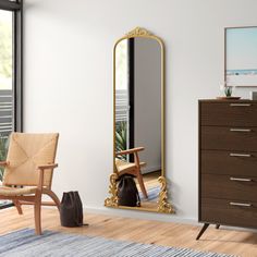 a living room with a chair and a large mirror on the wall next to a dresser