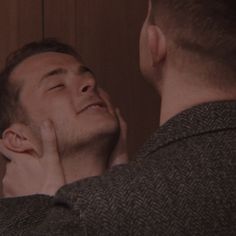 a man looking at another man's face in the mirror