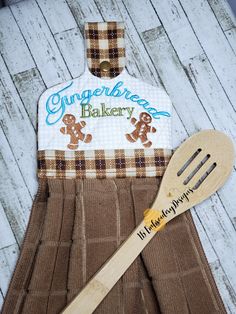 a wooden spatula with a gingerbread bakery logo on it next to a pair of oven mitts