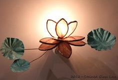 a light that is on the side of a wall next to some water lilies