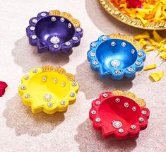 four different colored flower shaped dishes on the floor next to a plate with flowers in it