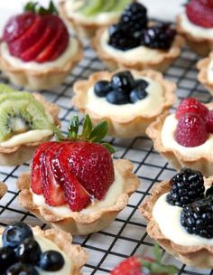 fruit tarts are arranged on a cooling rack