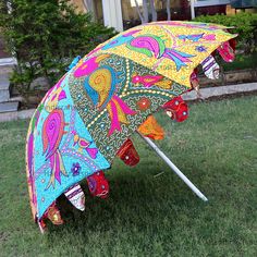 an open umbrella sitting on top of a lush green field in front of a house