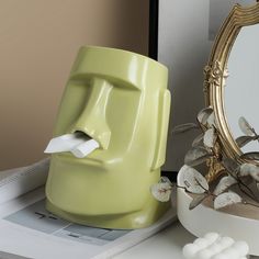 a yellow toothbrush holder sitting on top of a table next to a mirror and other items