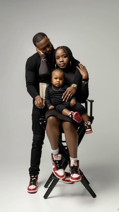 a man and woman are sitting on a chair with a small child in their lap