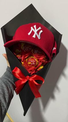 a baseball cap and candy in a black box with red ribbon around the brim