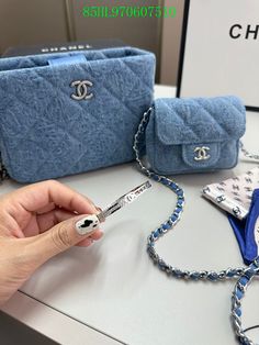 a person is holding a chain around a purse and it's contents on a table