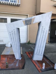 two large metal sculptures sitting on top of cement blocks in front of a garage door