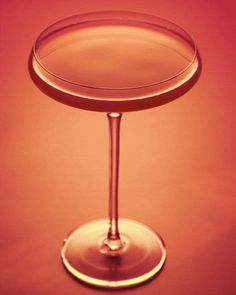 a wine glass sitting on top of a table next to a red wall and floor