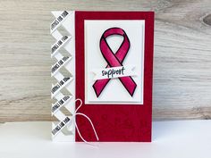 a card with a pink ribbon on it that says support in black and white lettering