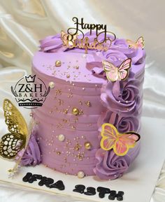 a birthday cake with purple frosting and butterflies on top, sitting on a white plate