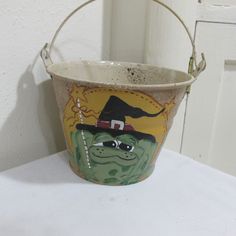 a bucket with a painting on it sitting on a table