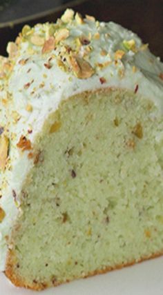 a piece of cake with white frosting and nuts on top sitting on a plate