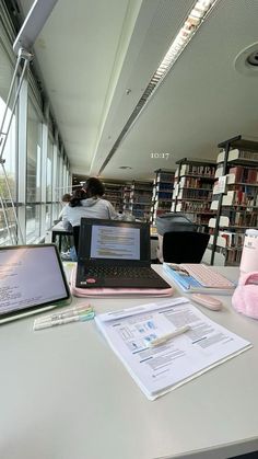 two laptops sitting on a table in a library