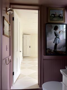 an open door leading to a bathroom with pictures on the wall and a white toilet