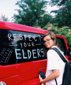 a woman standing next to a red truck with writing on it