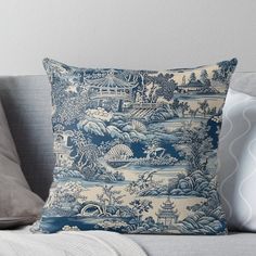 a blue and white toiler print pillow on a couch with grey throw pillows