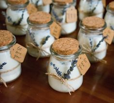 small jars filled with lavender candles on top of a wooden table