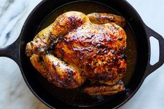 a roasted chicken in a cast iron skillet on a marble counter top, ready to be cooked