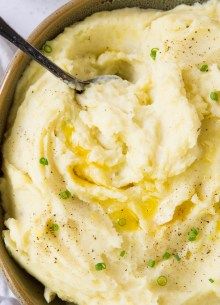 a bowl filled with mashed potatoes on top of a white cloth covered tablecloth