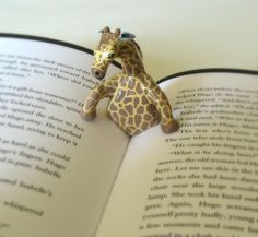 an open book with a giraffe figurine sitting on top of it