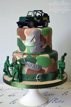 a three tiered cake decorated with camouflage and army figures, including an army jeep