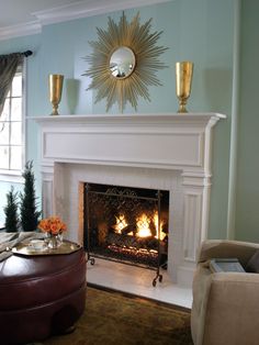 a fire place in a living room next to a couch and coffee table with candles on it