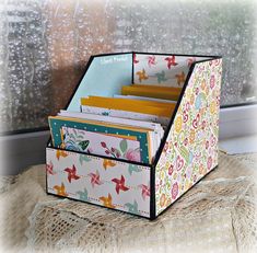 a close up of a box on a window sill filled with cards and folders